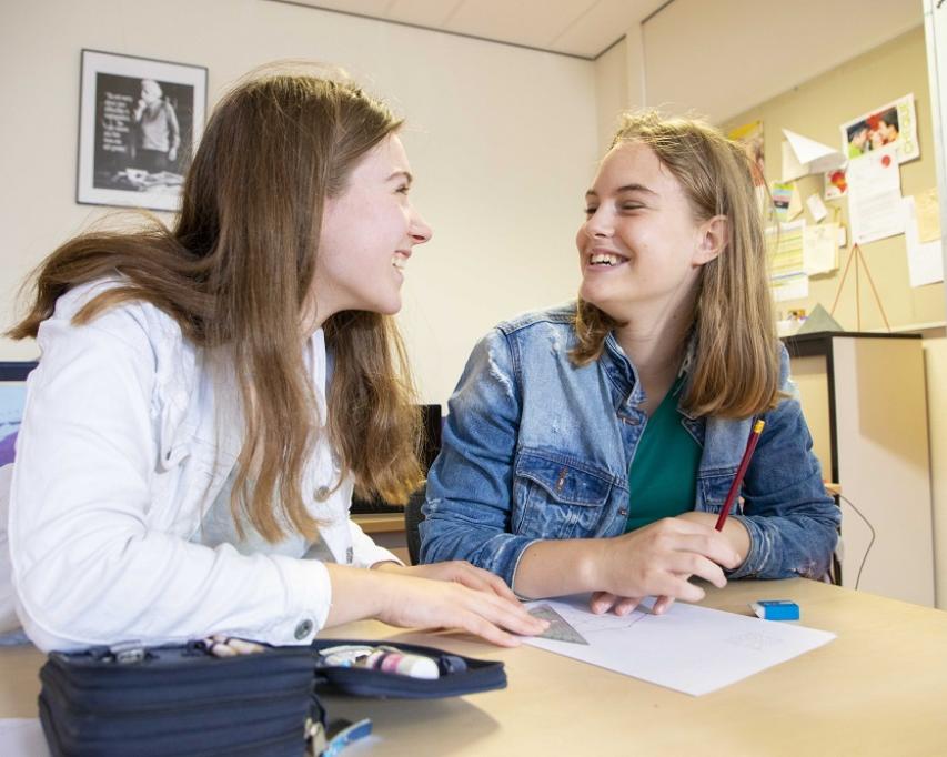 Twee meisjes kijken lachend naar elkaar