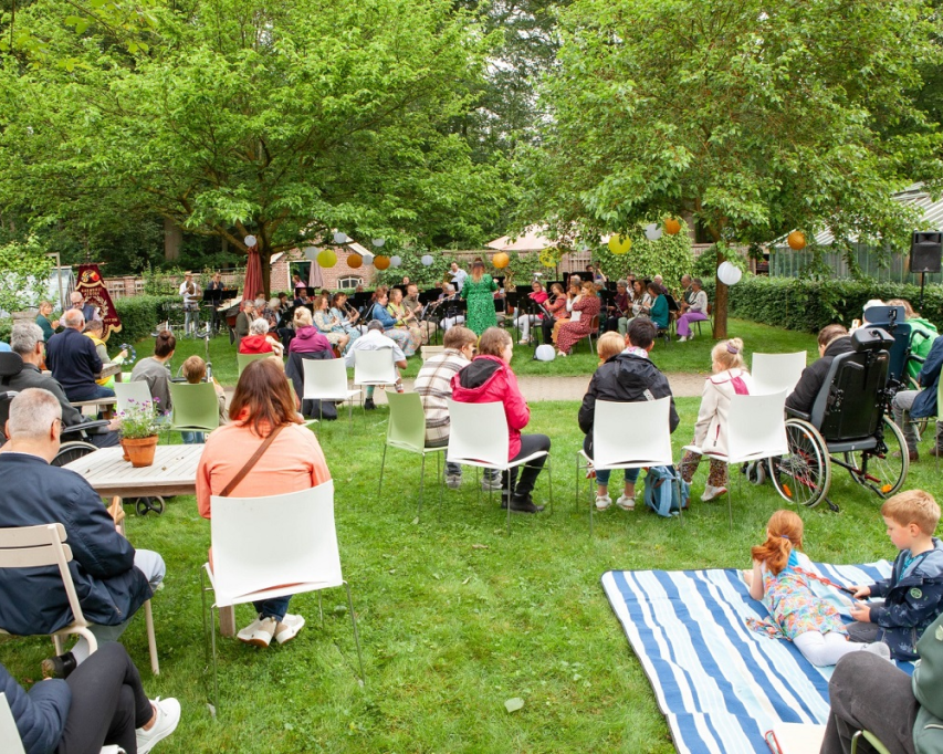 Mensen zitten op stoelen in de moestuin in doorn