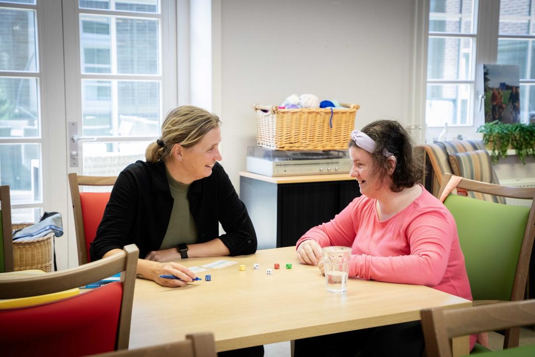 Bewoner en begeleider doen aan tafel een spelletje