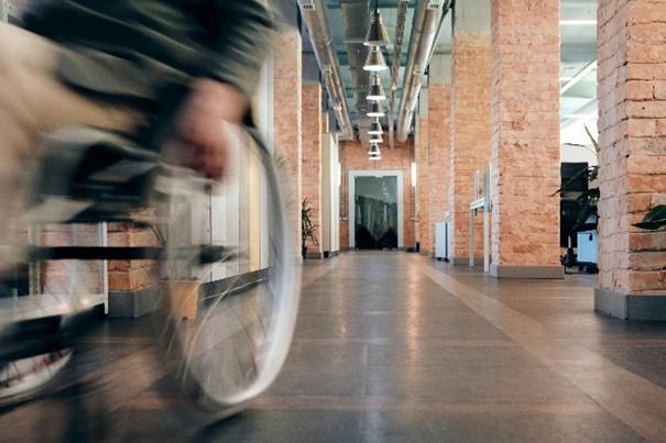 Een persoon in een rolstoel die zich in een kantooromgeving voortbeweegt