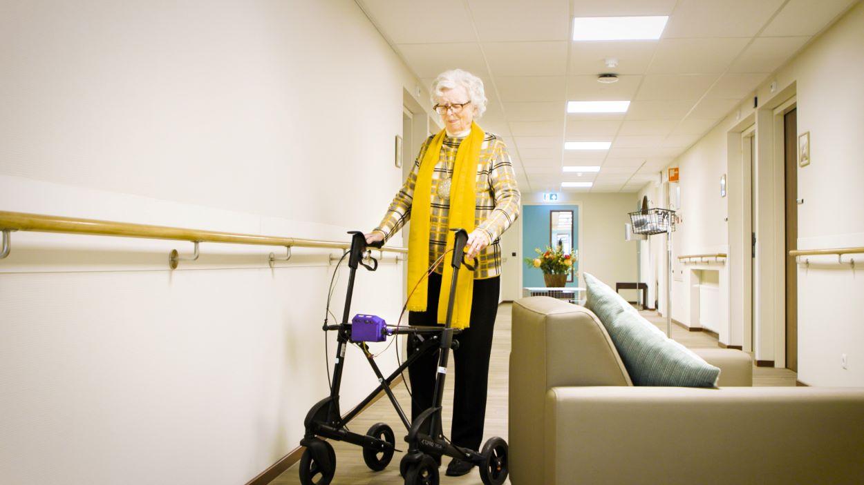 Cliënt in gang met slimme rollator die haar om bank heen leidt