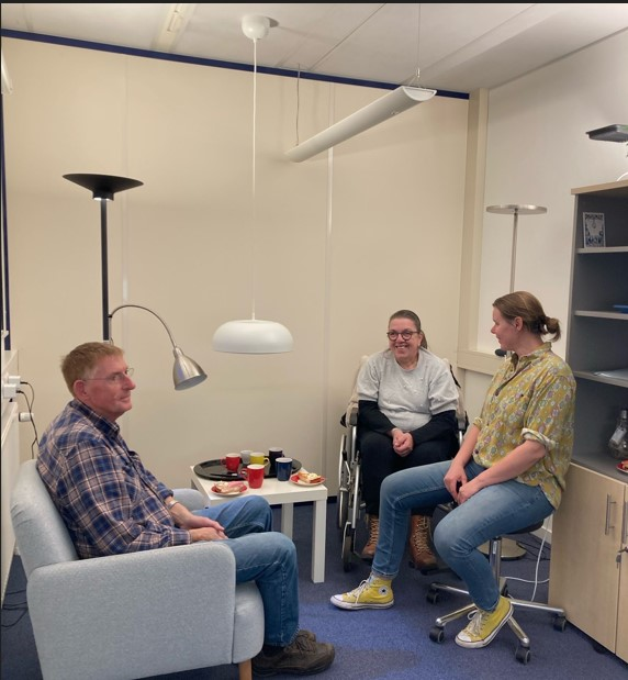 Drie personen zitten bij elkaar in een ruimte waar verschillende verlichtingselementen te zien zijn