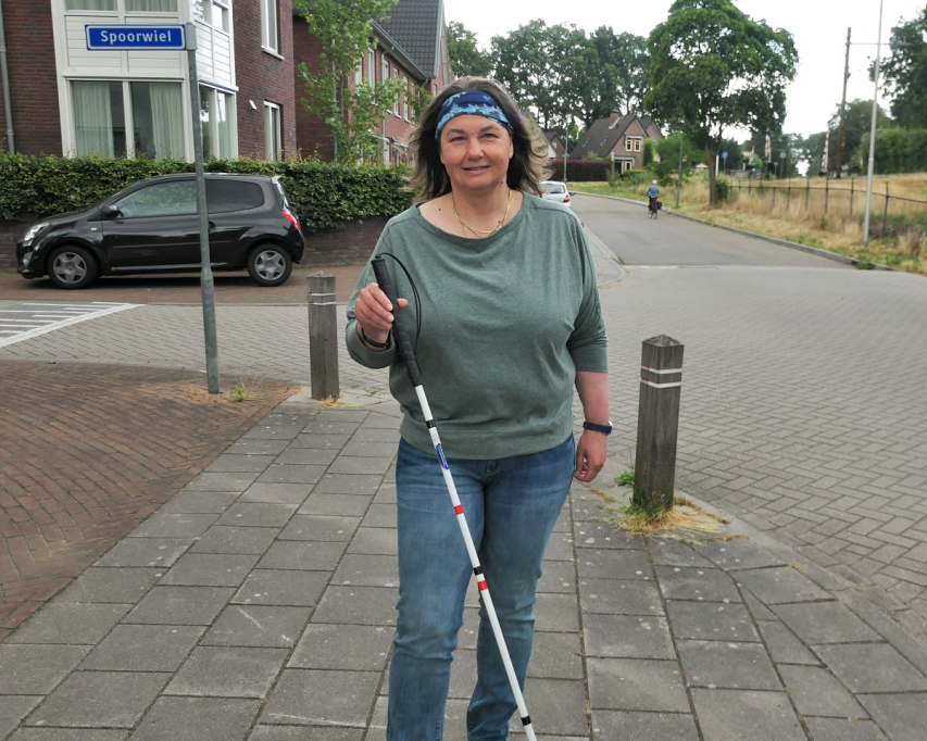 Michaela du Pon staat met haar taststok op een stoeprand.
