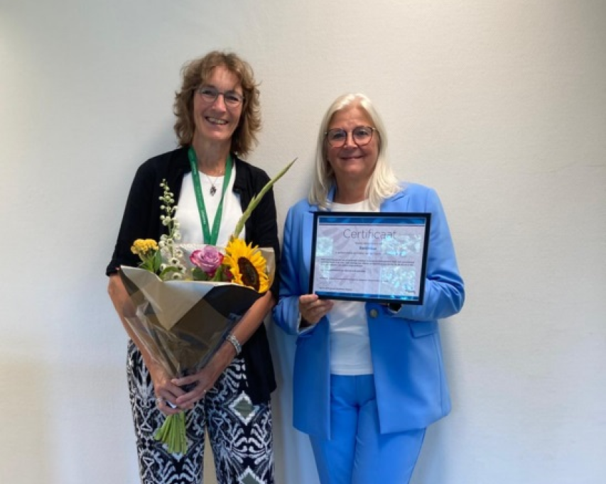 Twee vrouwen met bos bloemen en certificaat