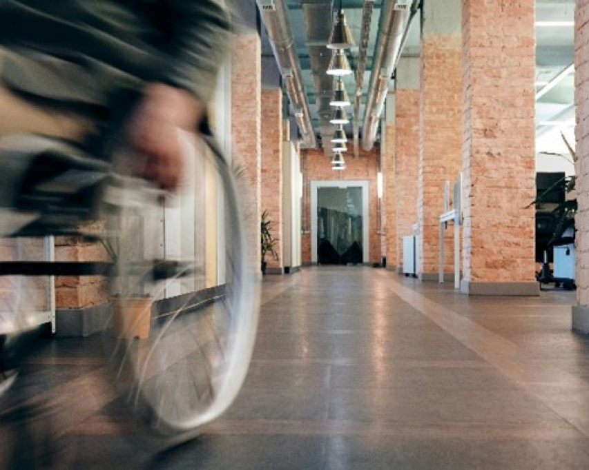 man in rolstoel rijdt zelfstandig door gebouw