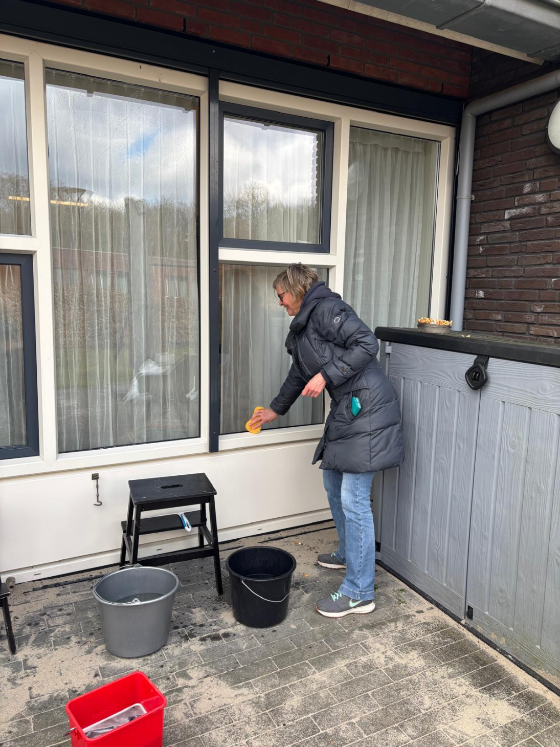Julianne wast de ramen aan de buitenkant van een woning