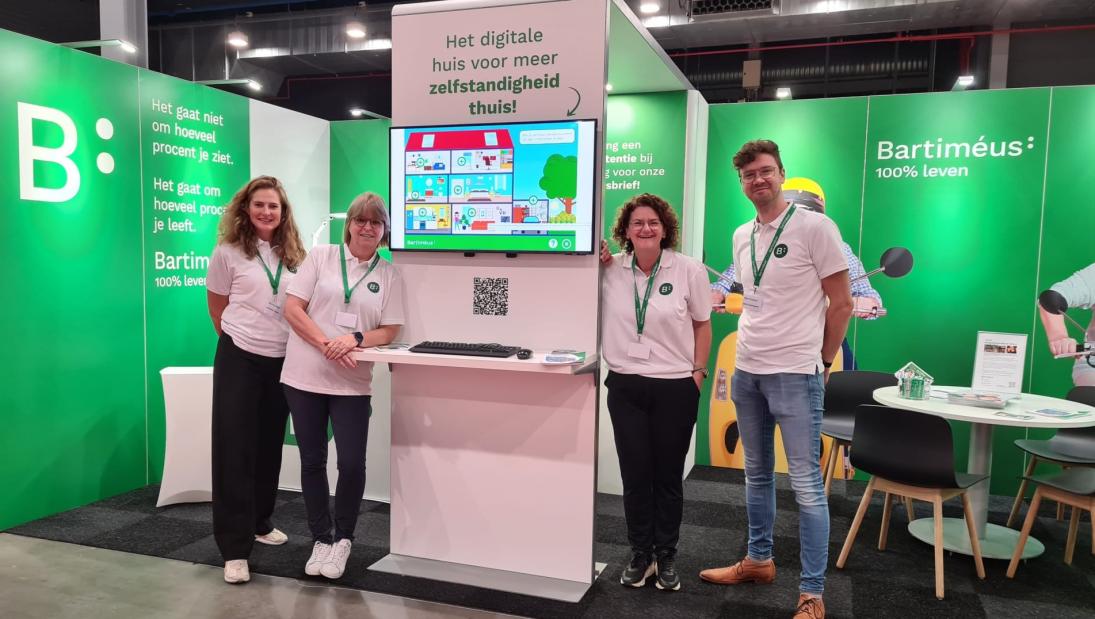 Beursteam van 4 medewerkers Bartiméus vooraan in de stand