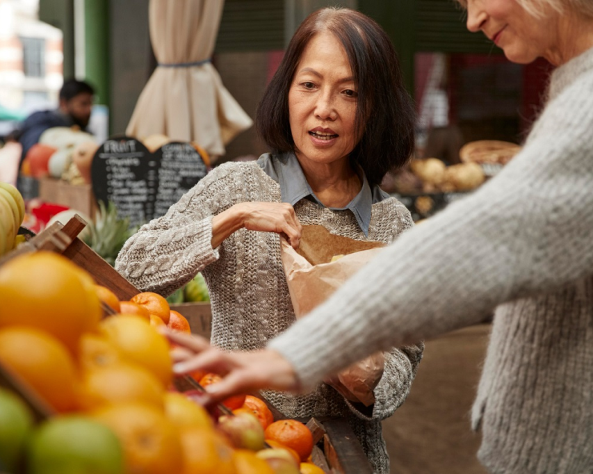 Vrouw doet fruit in zak in supermarkt