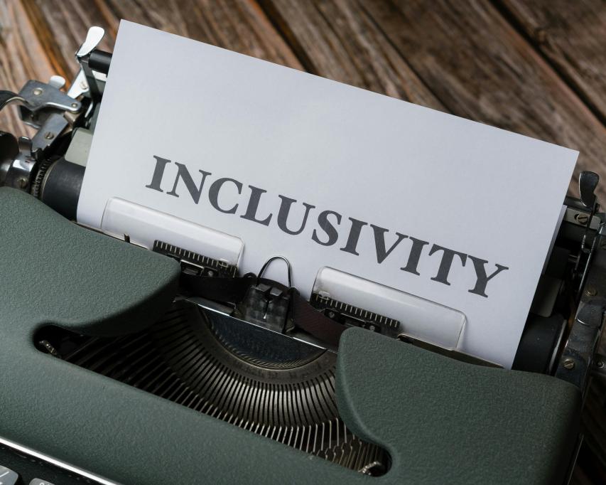 Een ouderwetse typemachine met wit A4 erin met de tekst inclusivity erop