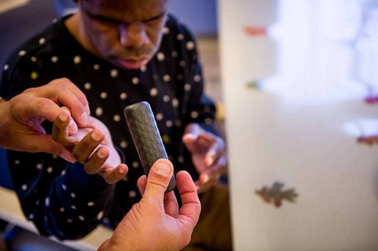 begeleider geeft doofblinde bewoner handvat van stuur