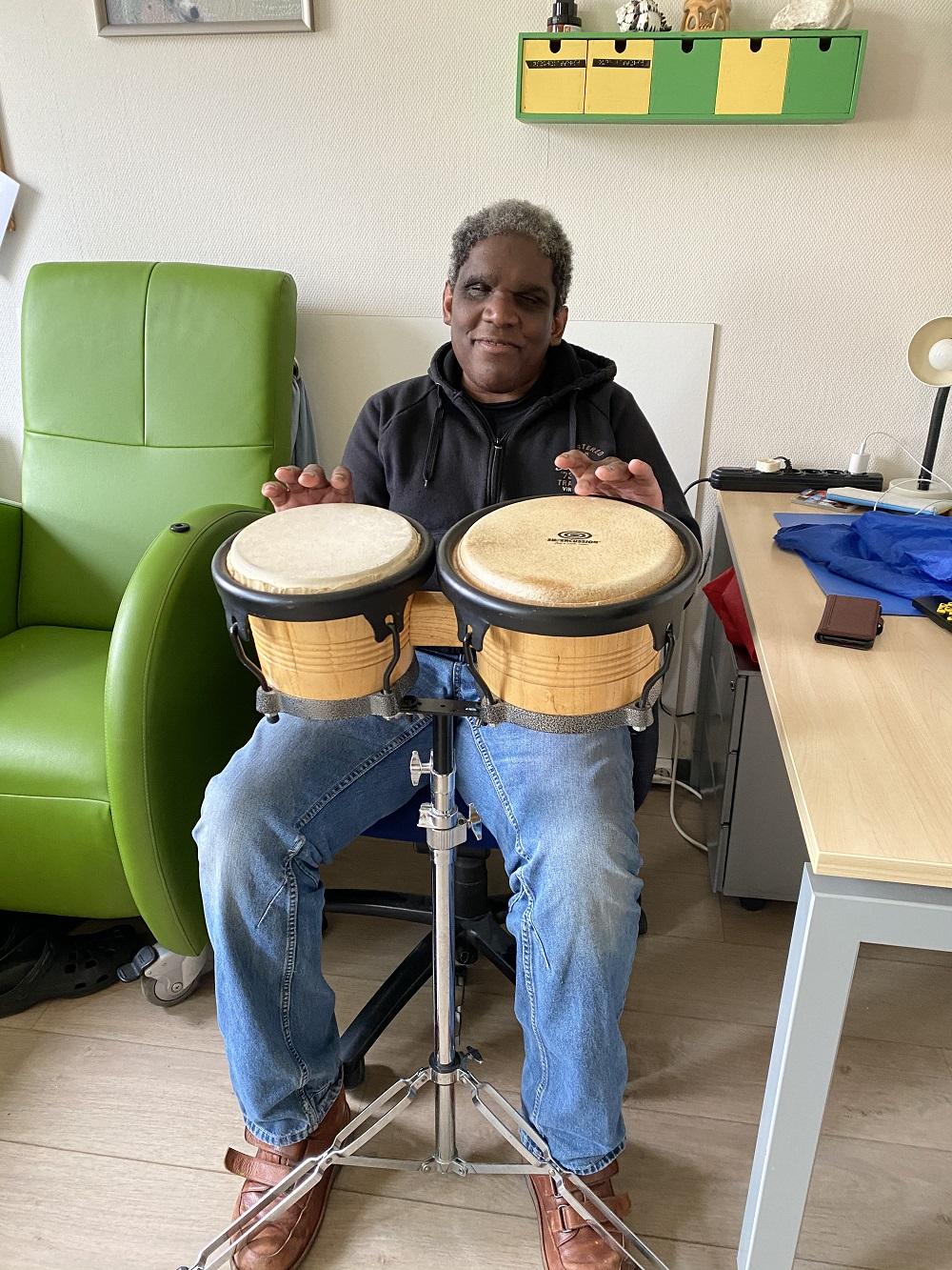 Bewoner Gregory speelt trommel op zijn appartement.