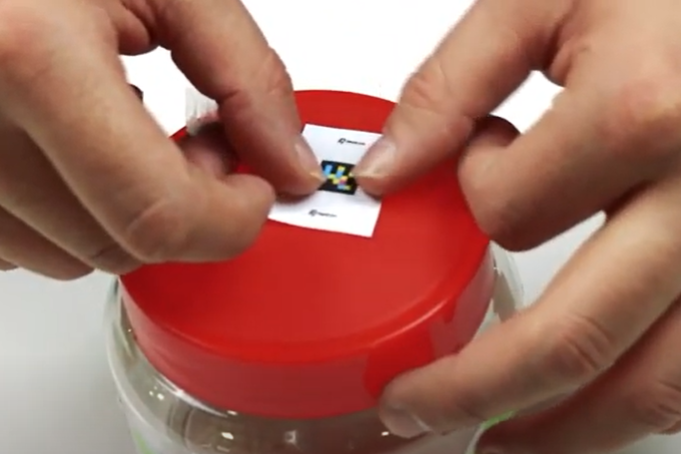 je plakt een label met een plakbandje op een object, op de foto is dat de deksel van een potje